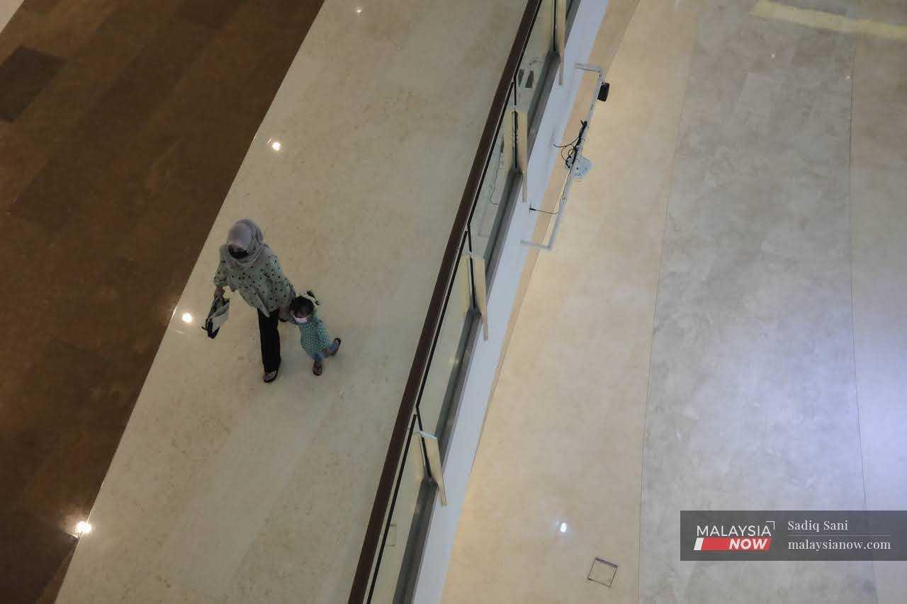 Seorang wanita bersama anak perempuannya di sebuah pasar raya di Putrajaya.