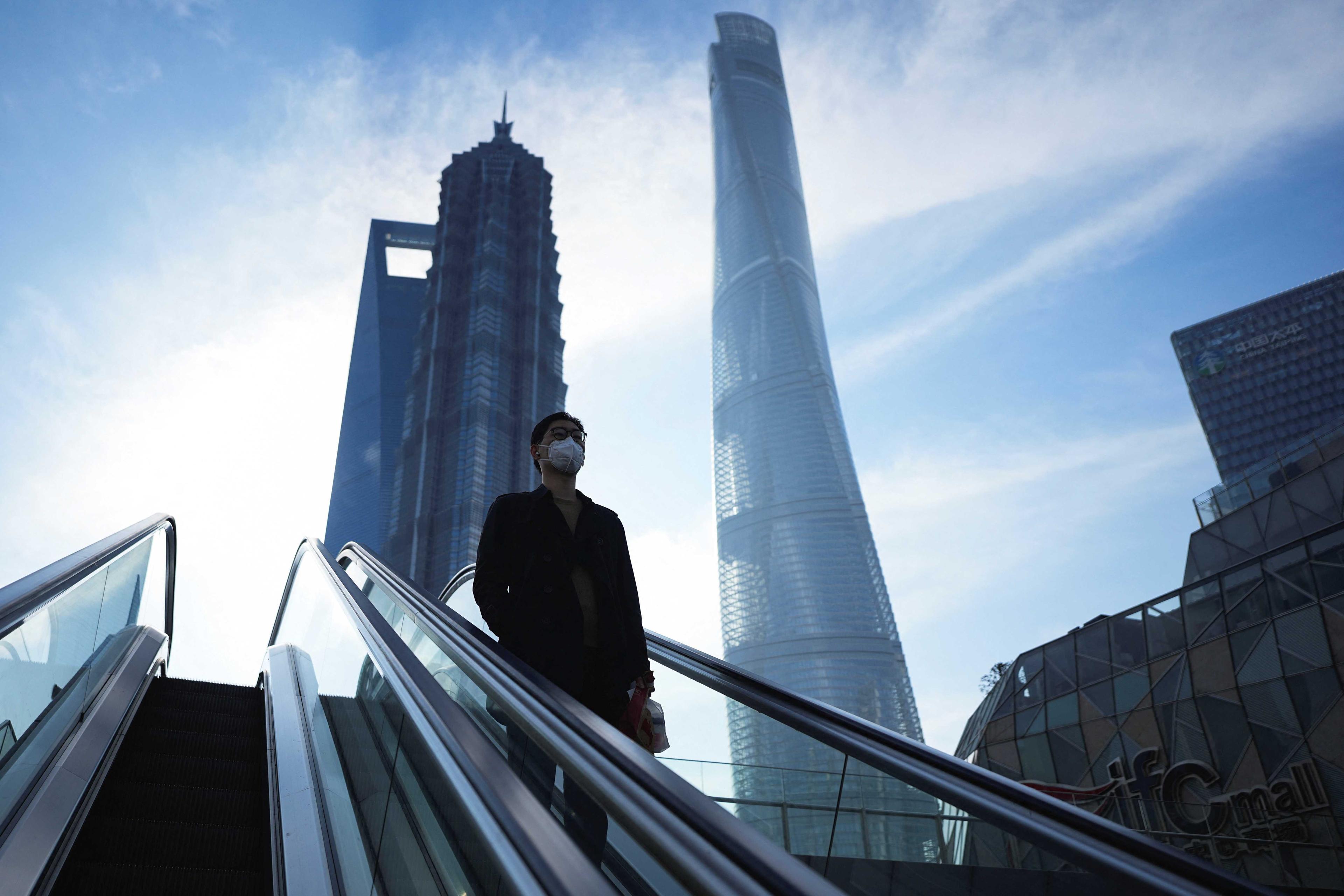 A man rides an escalator near office towers in the Lujiazui financial district, ahead of the National People's Congress (NPC), in Shanghai, China, Feb 28. Photo: Reuters