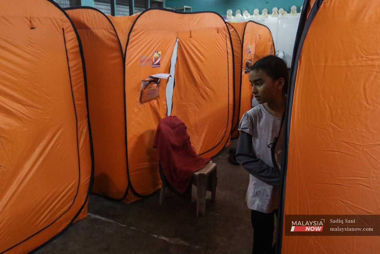 Gambar fail menunjukkan seorang remaja perempuan keluar dari khemahnya di pusat pemindahan banjir di SK Sungai Binjai, Klang pada 11 November 2022.