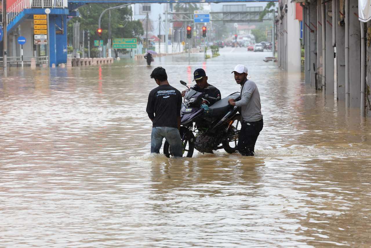 Pekerja bengkel mengalihkan motosikal ke kawasan tinggi di Bandar Kota Tinggi, Johor, 2 Mac. Gambar: Bernama