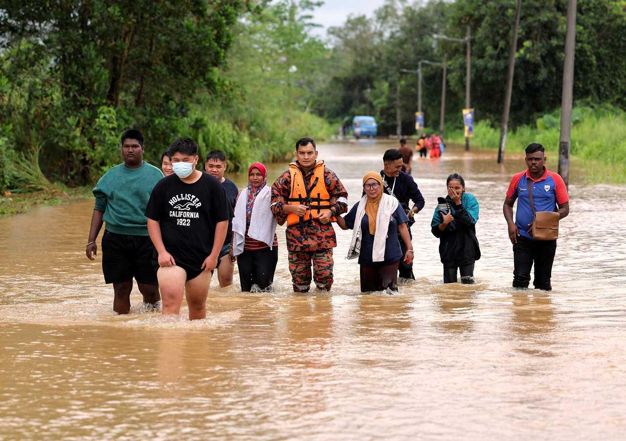 A member of the fire and rescue department guides people through the floodwaters at Kota Tinggi in Johor, March 1. Photo: Bernama