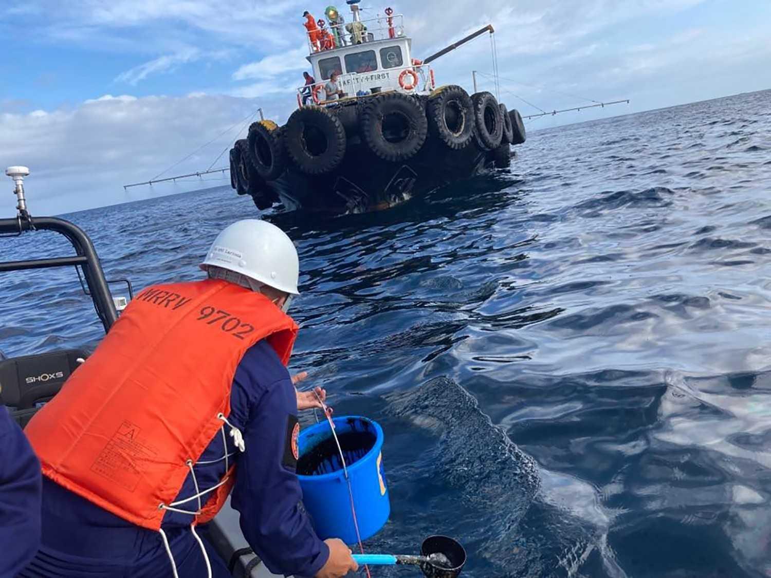 In this handout photo received from the Philippine Coast Guard and taken on March 2, a coast guard personnel collects water sample from of an oil spill in the waters off Naujan, Oriental Mindoro. Photo: AFP 