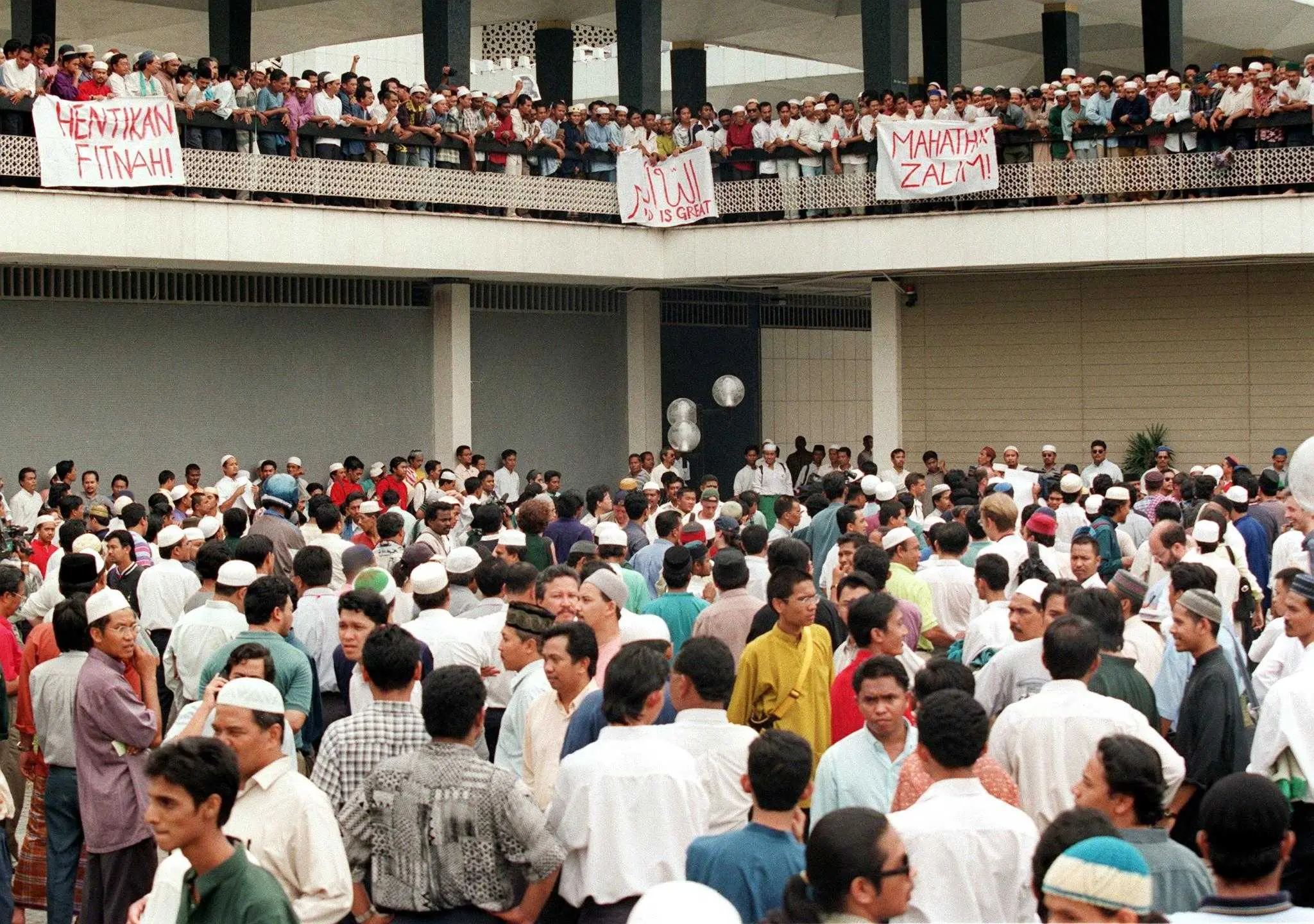 Sebahagian penyokong Anwar Ibrahim berdemonstrasi di perkarangan Masjid Negara ketika kemuncak Reformasi bawaan Anwar di Kuala Lumpur pada 25 September, 1998. Penyokongnya membentangkan sepanduk berbunyi 'Hentikan Fitnah' dan 'Mahathir Zalim'. Gambar: AFP