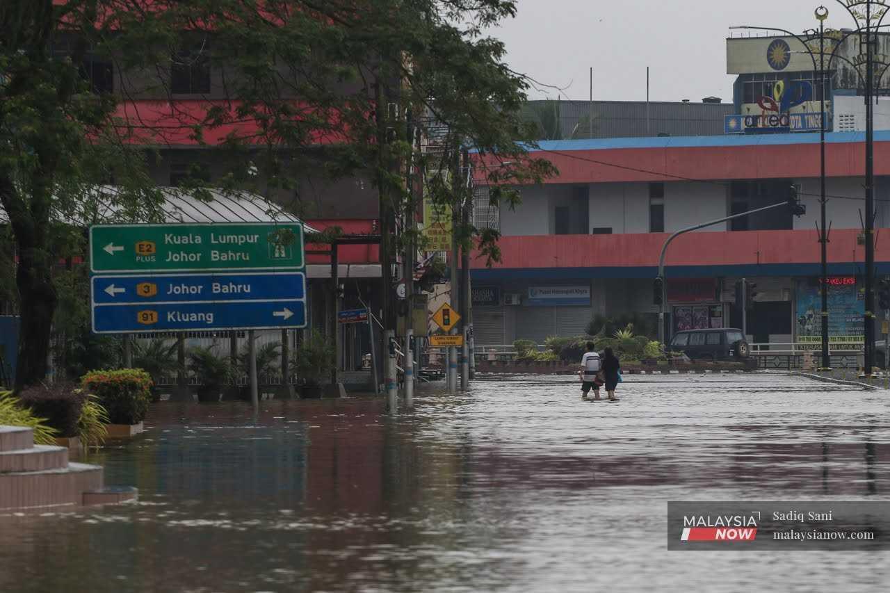 Penduduk meredah air banjir setinggi paras lutut di Kota Tinggi, Johor, 5 Mac.