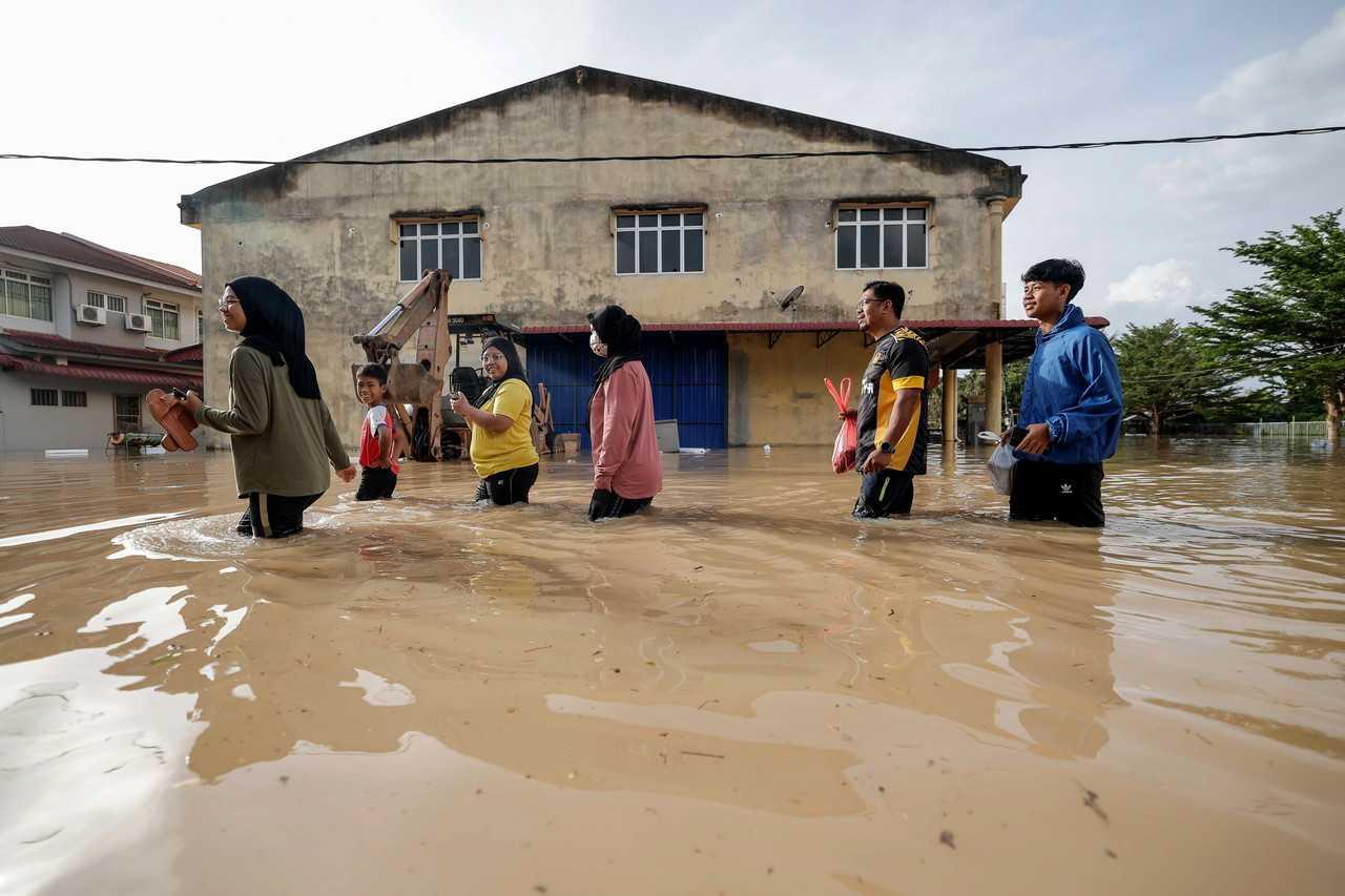 Family members wade through flood water at Seri Medan Batu Pahat in Batu Pahat, Johor, March 5. Photo: Bernama