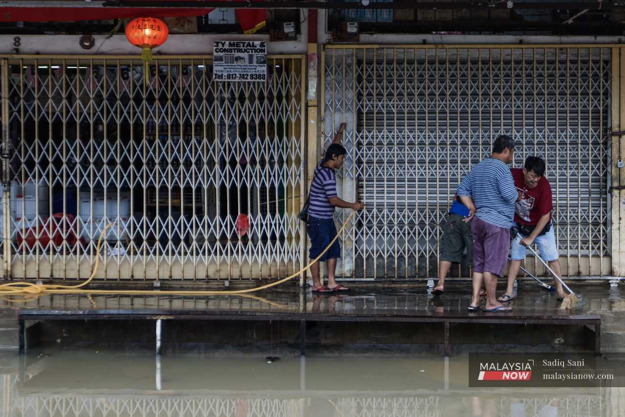 Shop owners scrub the front of their units in Kota Tinggi, Johor, as the flood water begins to subside. 