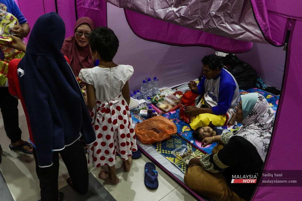 A family sits in their tent at a flood evacuation centre in Kota Tinggi, Johor. 
