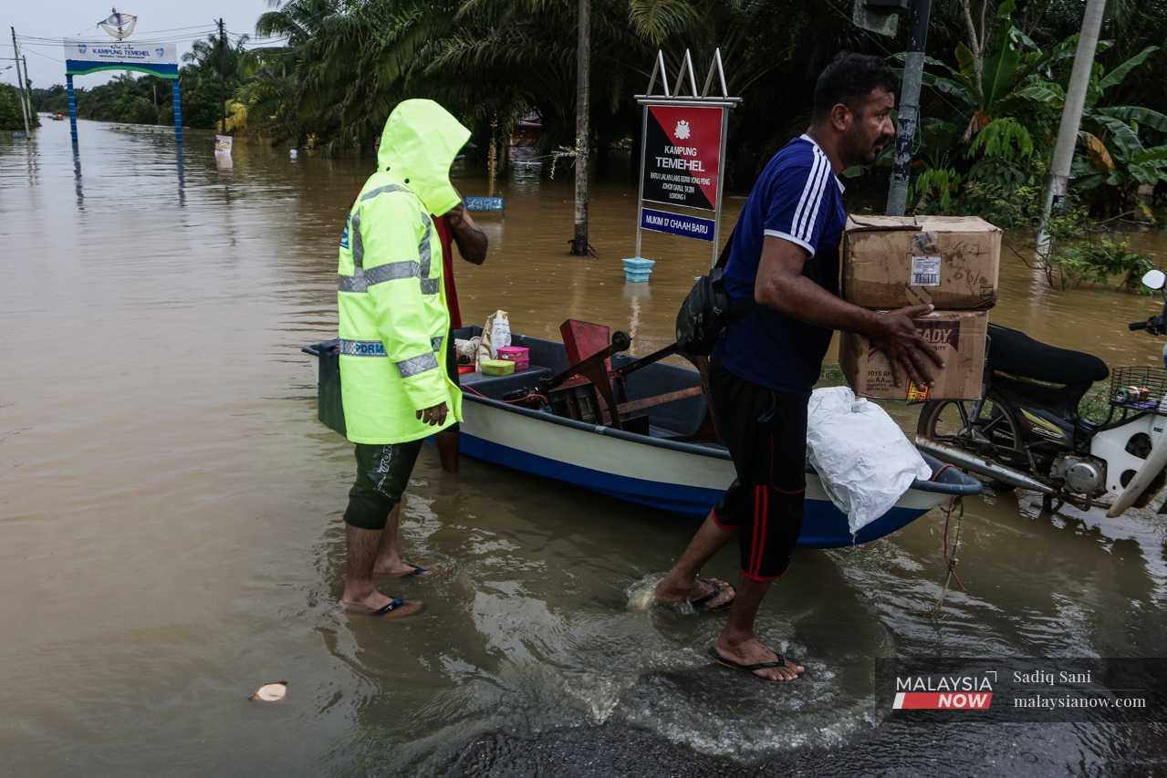Two men distribute supplies to flood victims at Kampung Temehel, Yong Peng.
