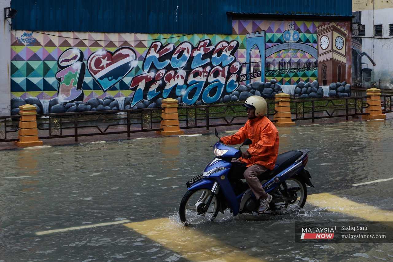A motorist rides through receding flood water in Kota Tinggi, Johor. 