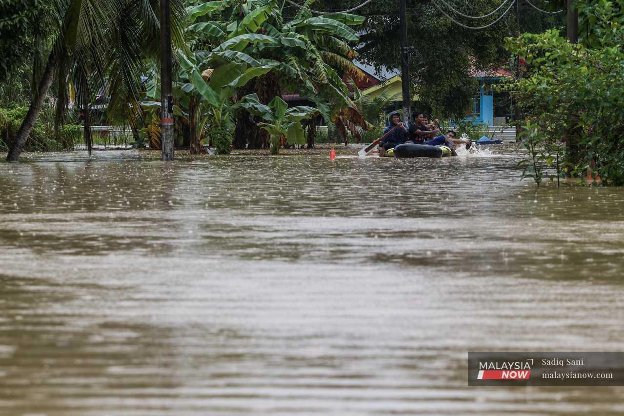 A group of boys paddle an inflatable boat in Kampung Melayu, Yong Peng.