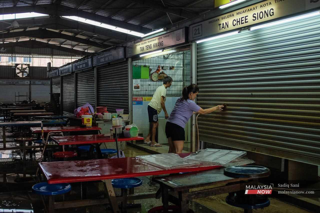 Traders clean their stalls after the flood water recedes at a food court in Kota Tinggi, Johor.