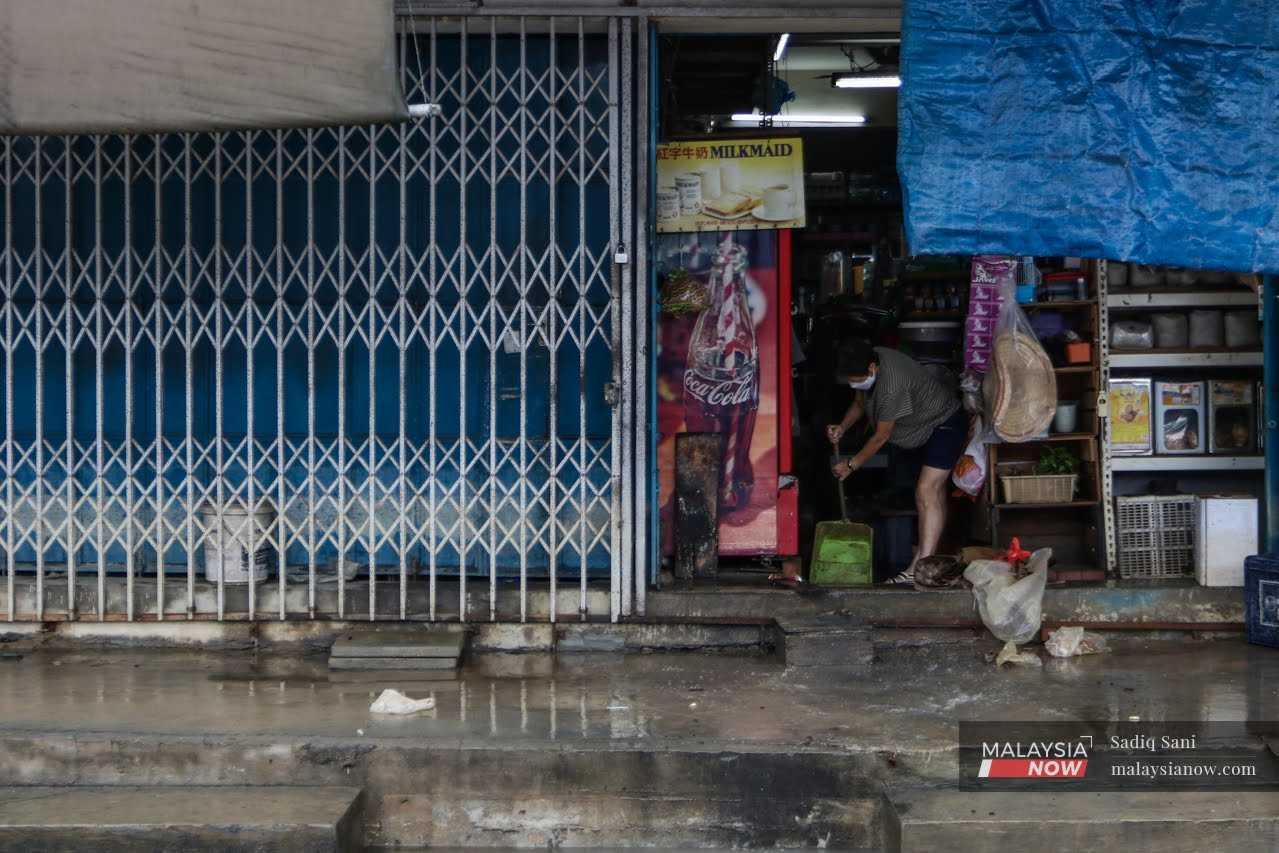 A woman cleans her store after the floods begin to subside in Kota Tinggi, Johor.