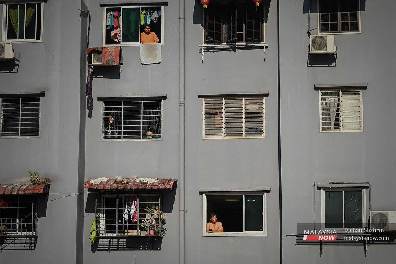 Residents look out through their unit windows at a low-cost flat in Cheras, Kuala Lumpur.