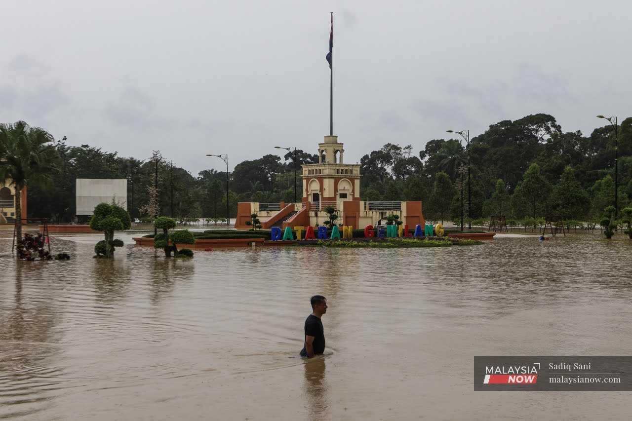 Penduduk meredah air banjir di hadapan Dataran Gemilang di Yong Peng, Johor pada 4 Mac lalu.