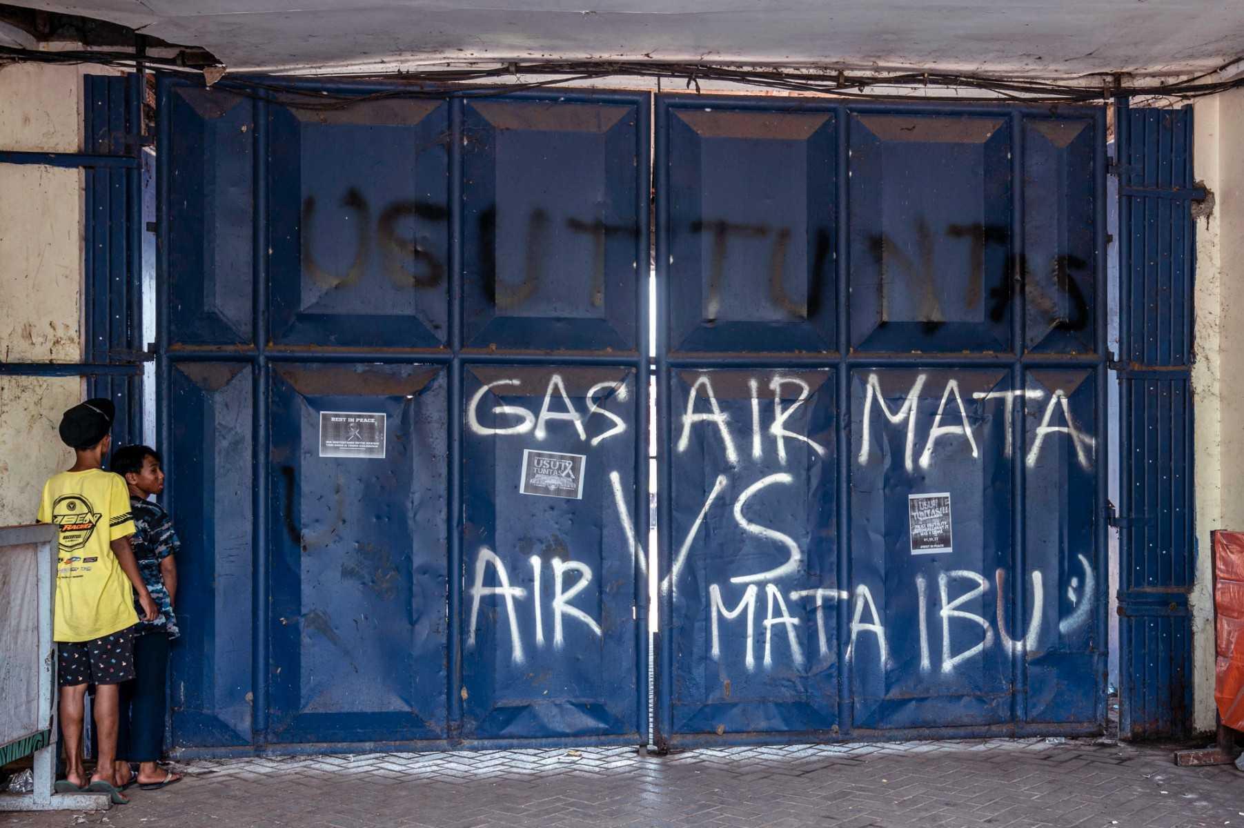 Two boys peep from the entrance of the stampede site at Kanjuruhan stadium in Malang, East Java on Oct 4, 2022. Photo: AFP