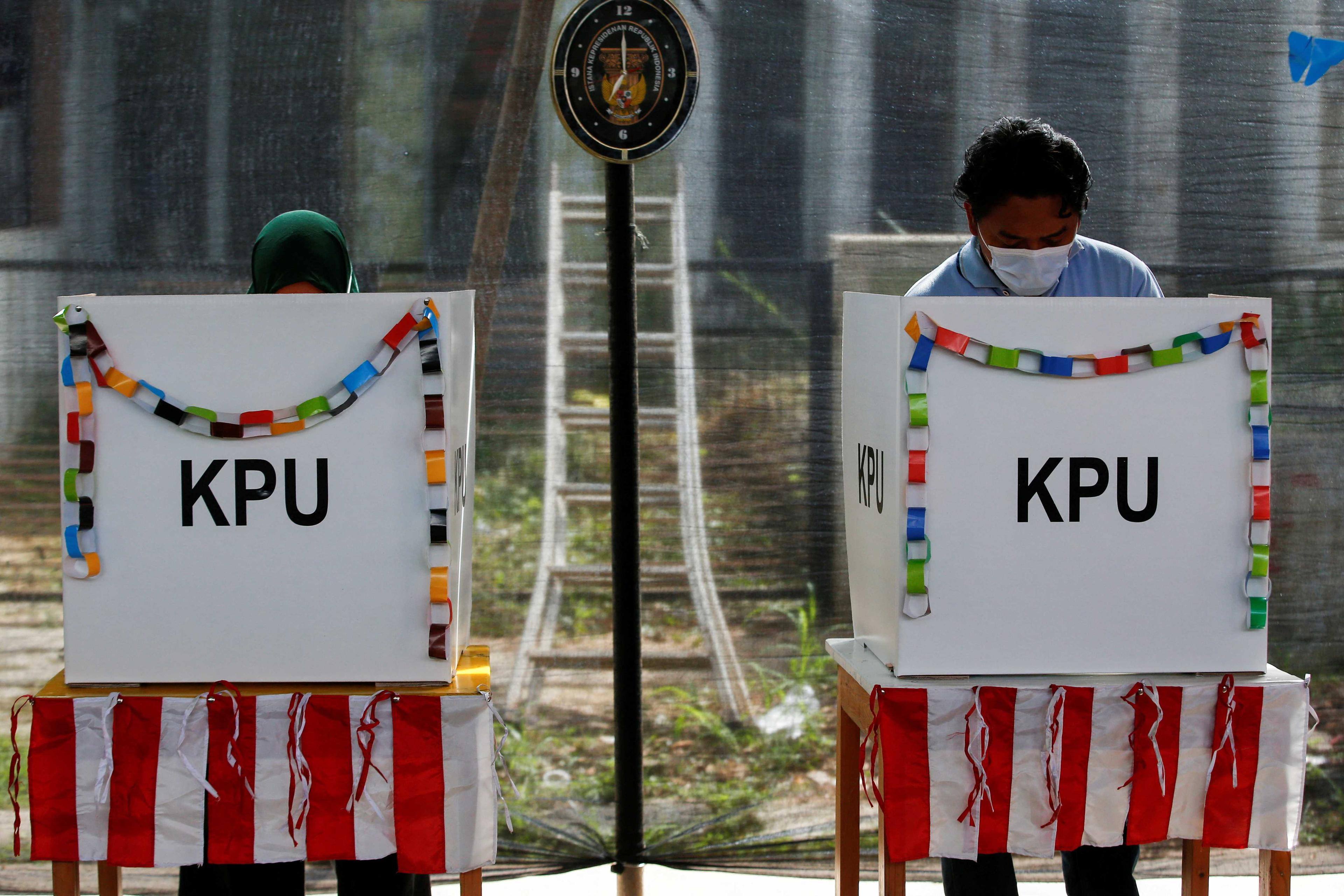 Voters wearing protective masks mark their ballots at a polling booth during regional elections in Tangerang, near Jakarta, Indonesia, Dec 9, 2020. Photo: Reuters