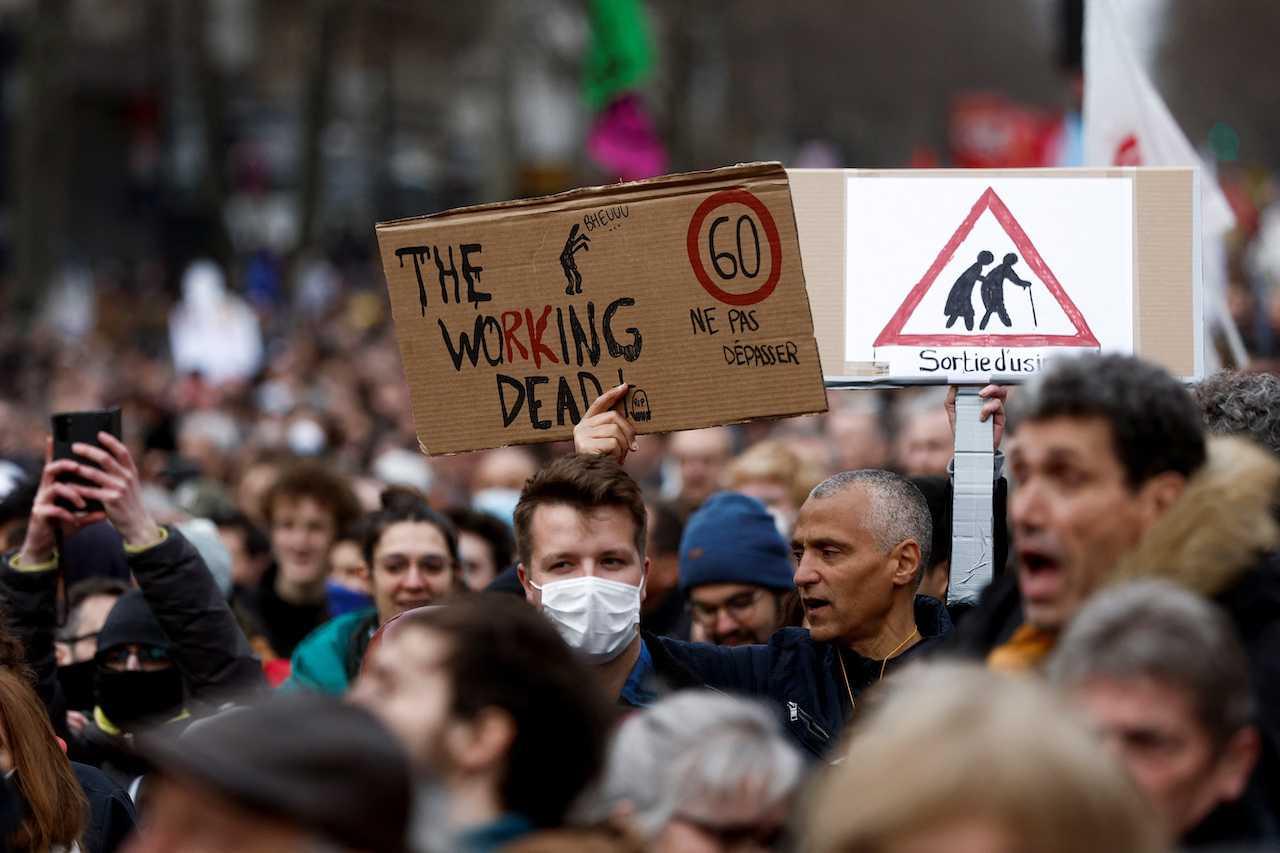 Demonstrators hold placards during a march against the government's pension reform plan in Paris, France, March 11. Photo: Reuters