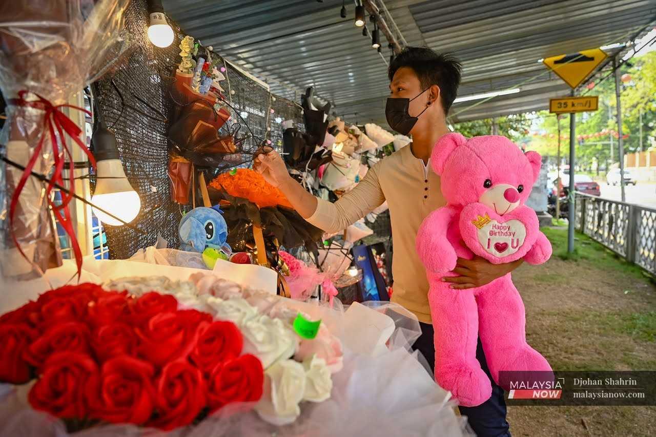 Seorang lelaki memegang patung beruang sambil memilih gubahan bunga di sebuah gerai sempena sambutan Hari Kekasih di Taman Kuchai pada 14 Februari.