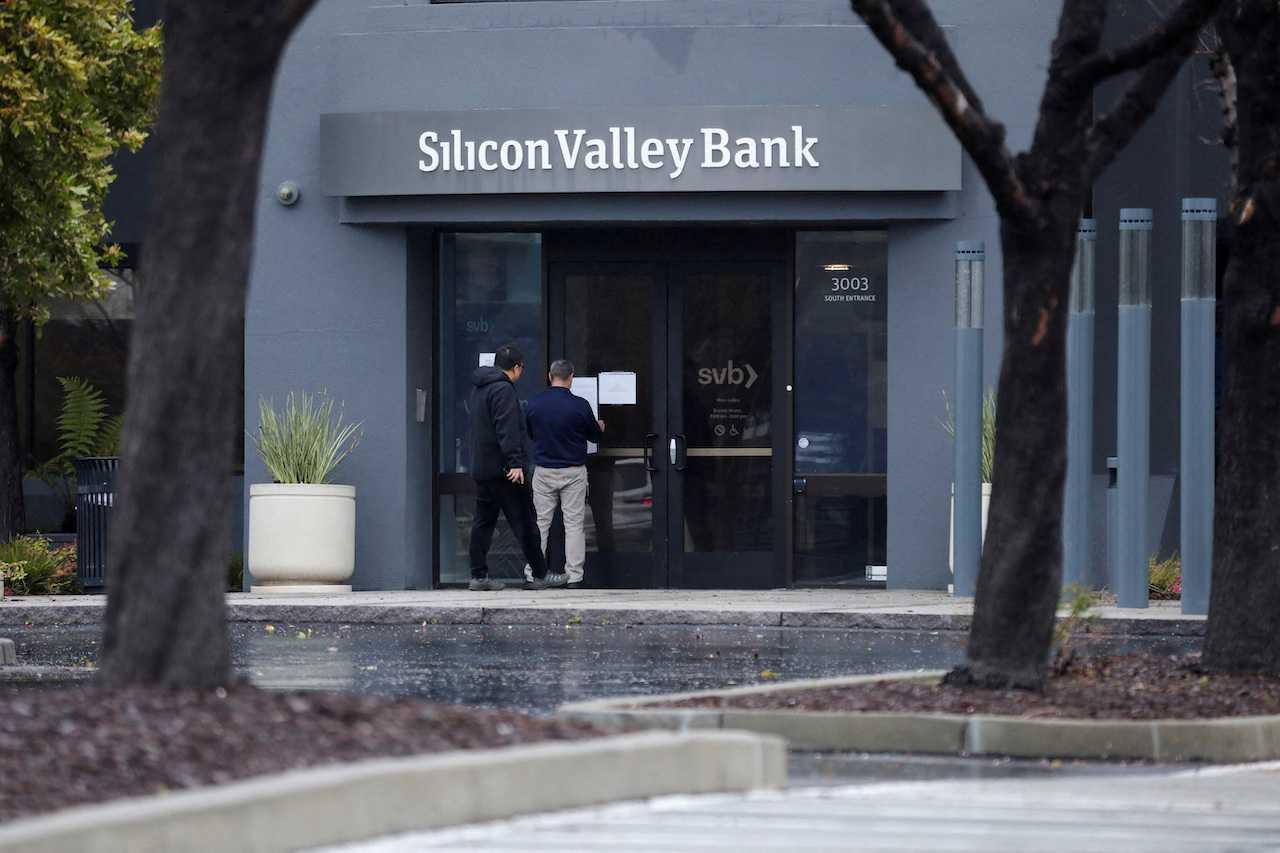 A man puts a sign on the door of the Silicon Valley Bank as an onlooker watches at the bank’s headquarters in Santa Clara, California, March 10. Photo: Reuters
