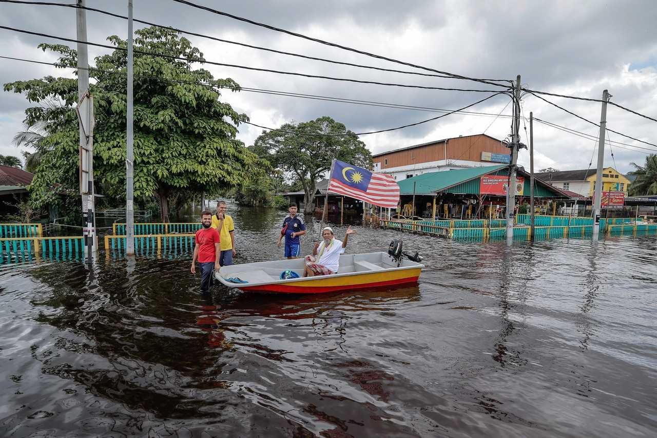 Penduduk tempatan meredah air banjir dengan menaiki bot di Parit Sulong, Batu Pahat, Johor, 9 Mac. Gambar: Bernama