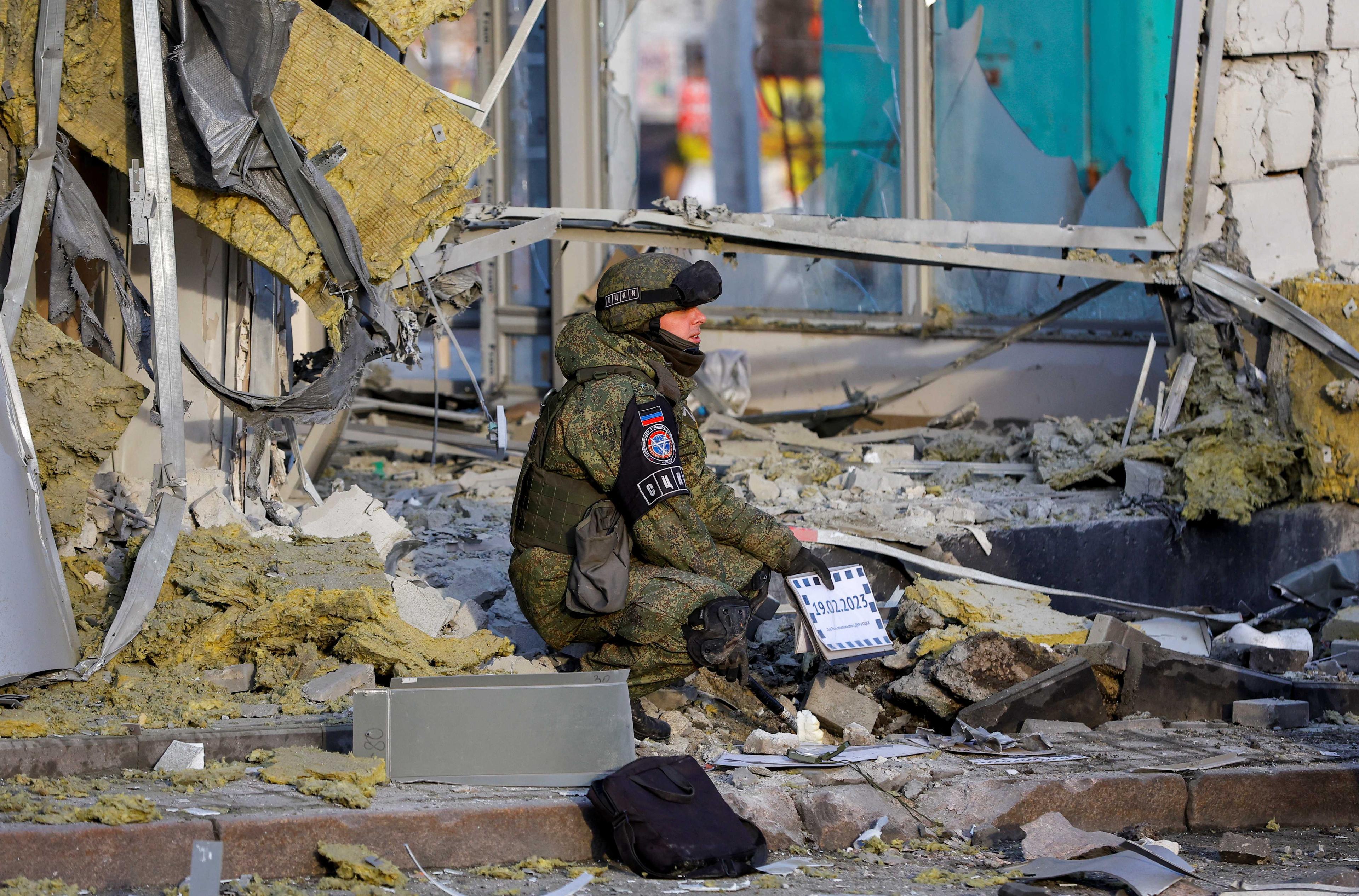Penyiasat tentera Rusia meneliti tempat kejadian selepas sebuah kedai rosak teruk akibat terkena tembakan dalam konflik Rusia-Ukraine di Donetsk, Ukraine yang dikuasai Rusia, 19 Februari. Gambar: Reuters