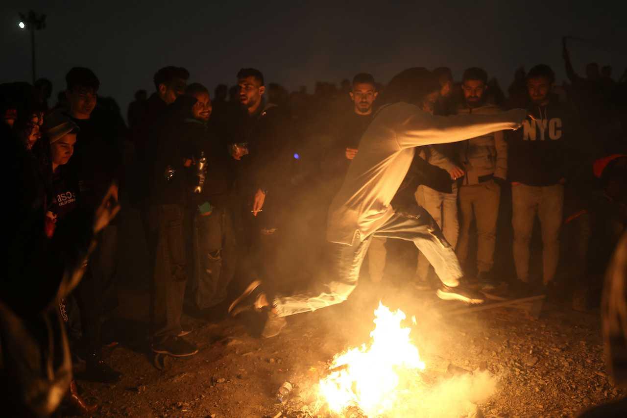 An Iranian woman jumps over a fire during the fire celebration at a park in Tehran, Iran, March 14. Photo: Reuters