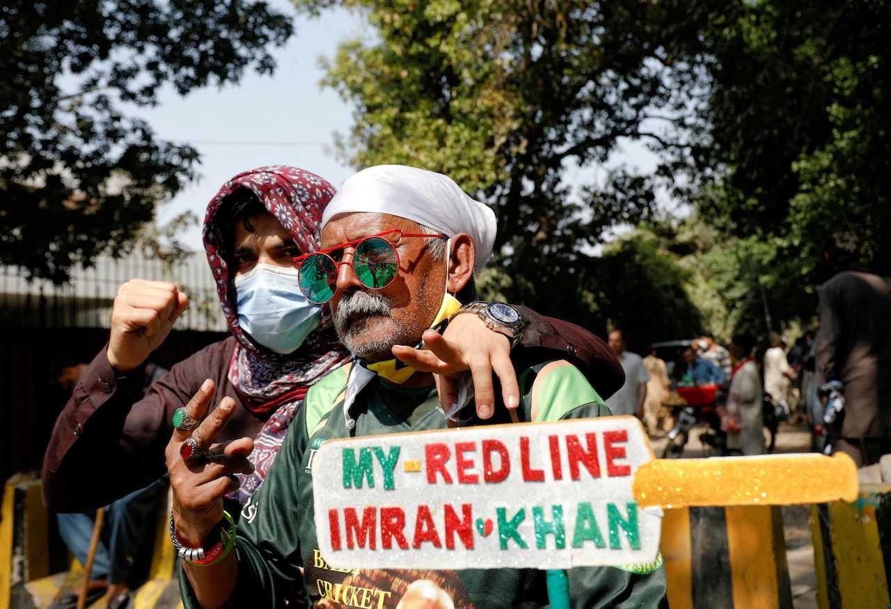 Supporters of former Pakistan prime minister Imran Khan pose with a placard in a shape of a cricket bat as they gather with others outside Khan's house, in Lahore, Pakistan, March 16. Photo: Reuters