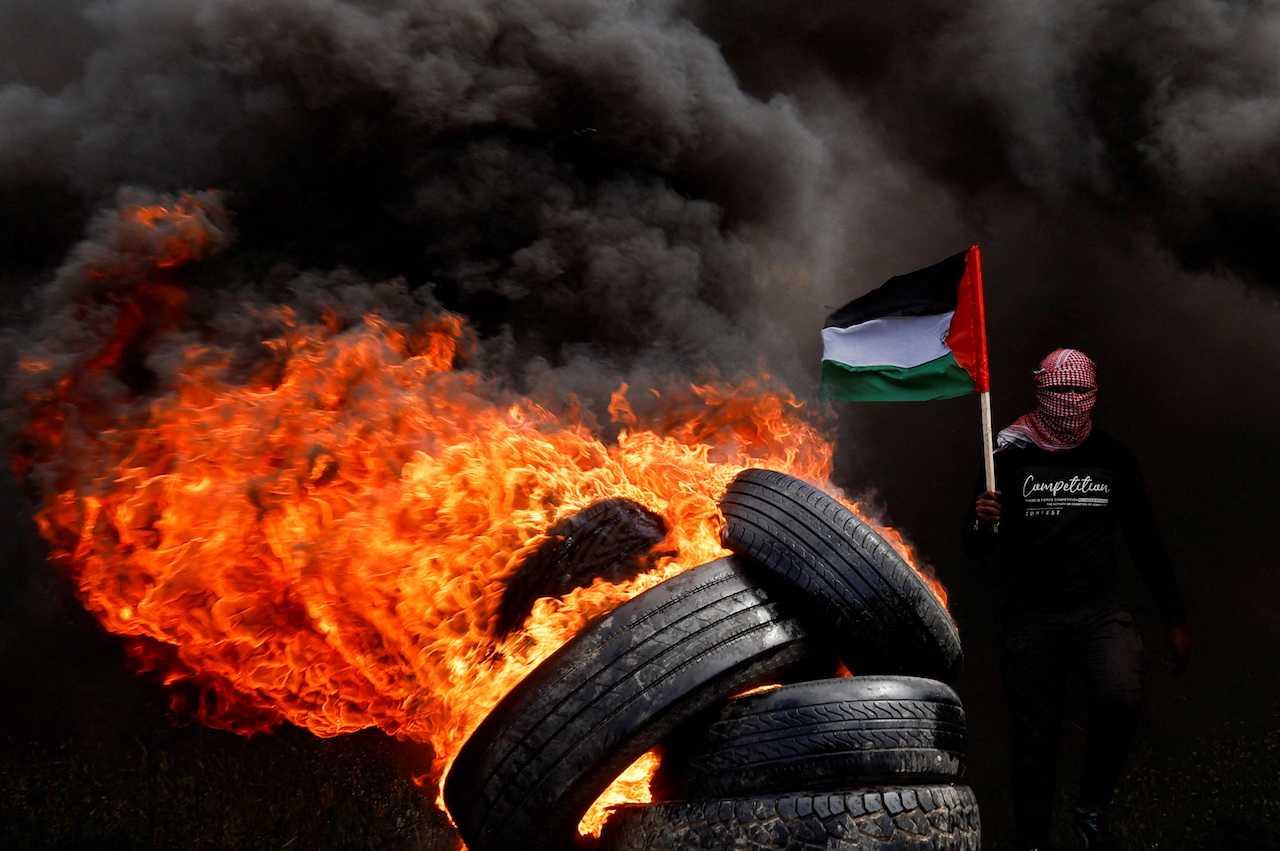 A man holds a Palestinian flag during a protest against Israeli-Palestinian meeting in Sharm el-Sheikh, at the Israel-Gaza border fence east of Gaza City, March 19. Photo: Reuters