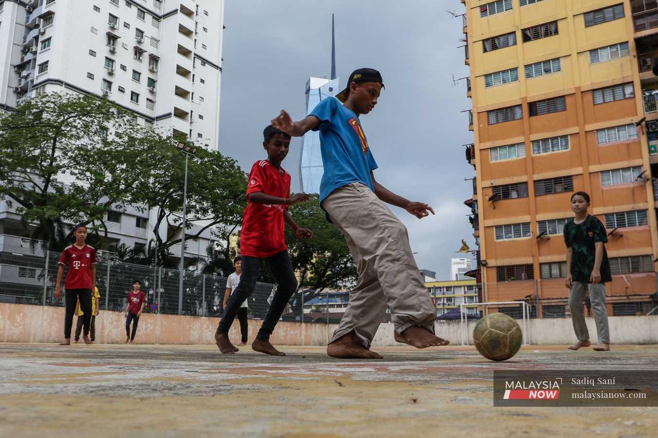 Outside, children play futsal barefoot against a backdrop of the world's second tallest building, the Merdeka 118 Tower.