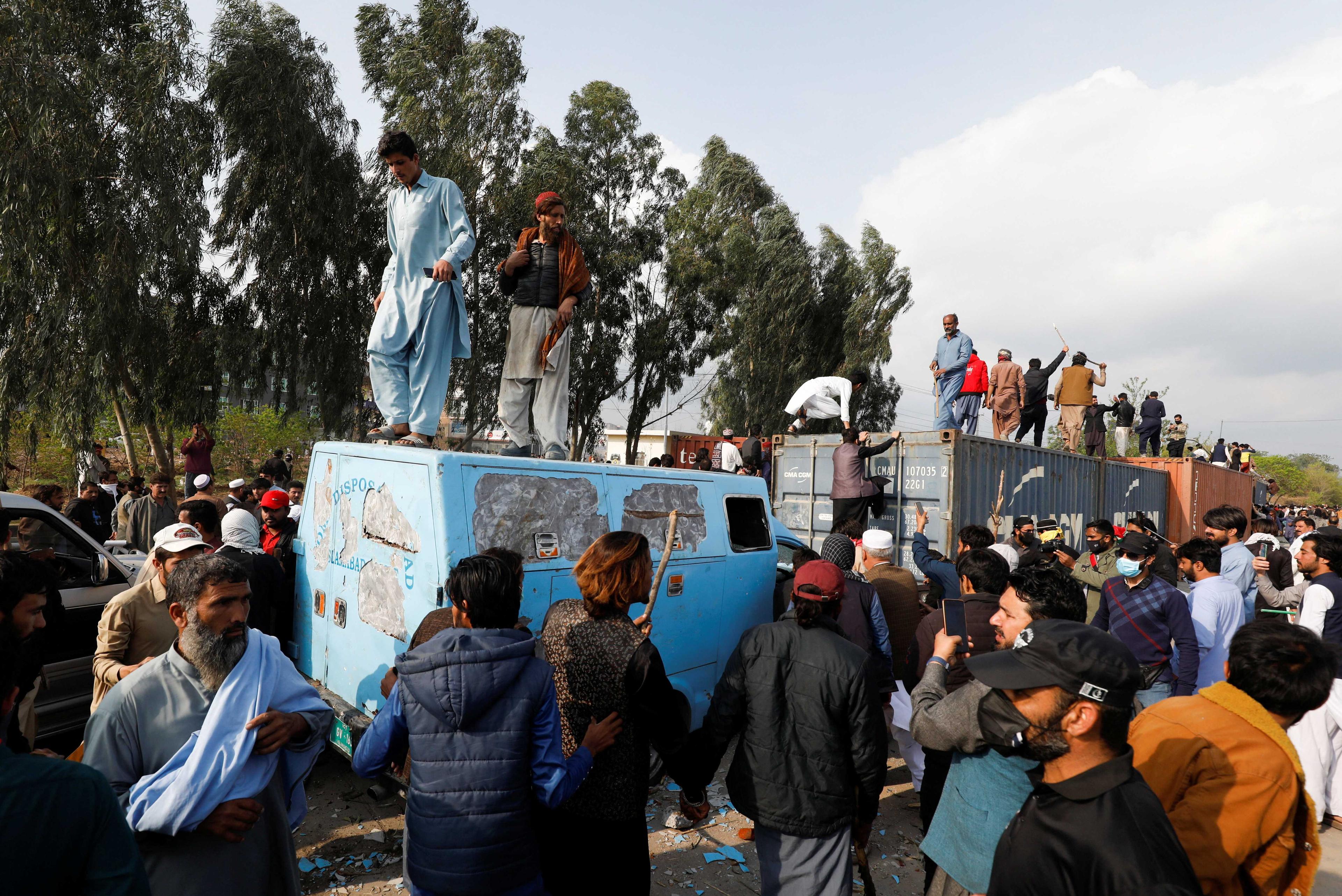 Supporters of former Pakistani Prime Minister Imran Khan climb on shipping containers, placed to block the road, during a clash outside the federal judicial complex in Islamabad, Pakistan March 18. Photo: Reuters