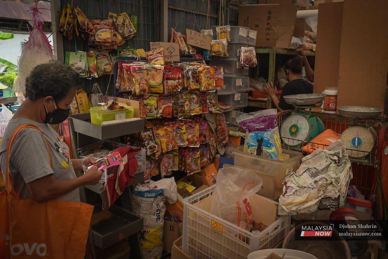 A customer looks at the price tag on a package at a dry goods shop in the Ampang market in Selangor.