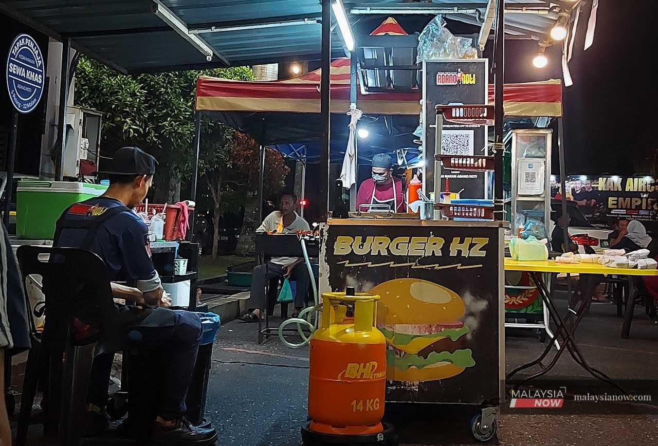 Traders wait at a roadside burger stall in Jitra, Kedah. 
