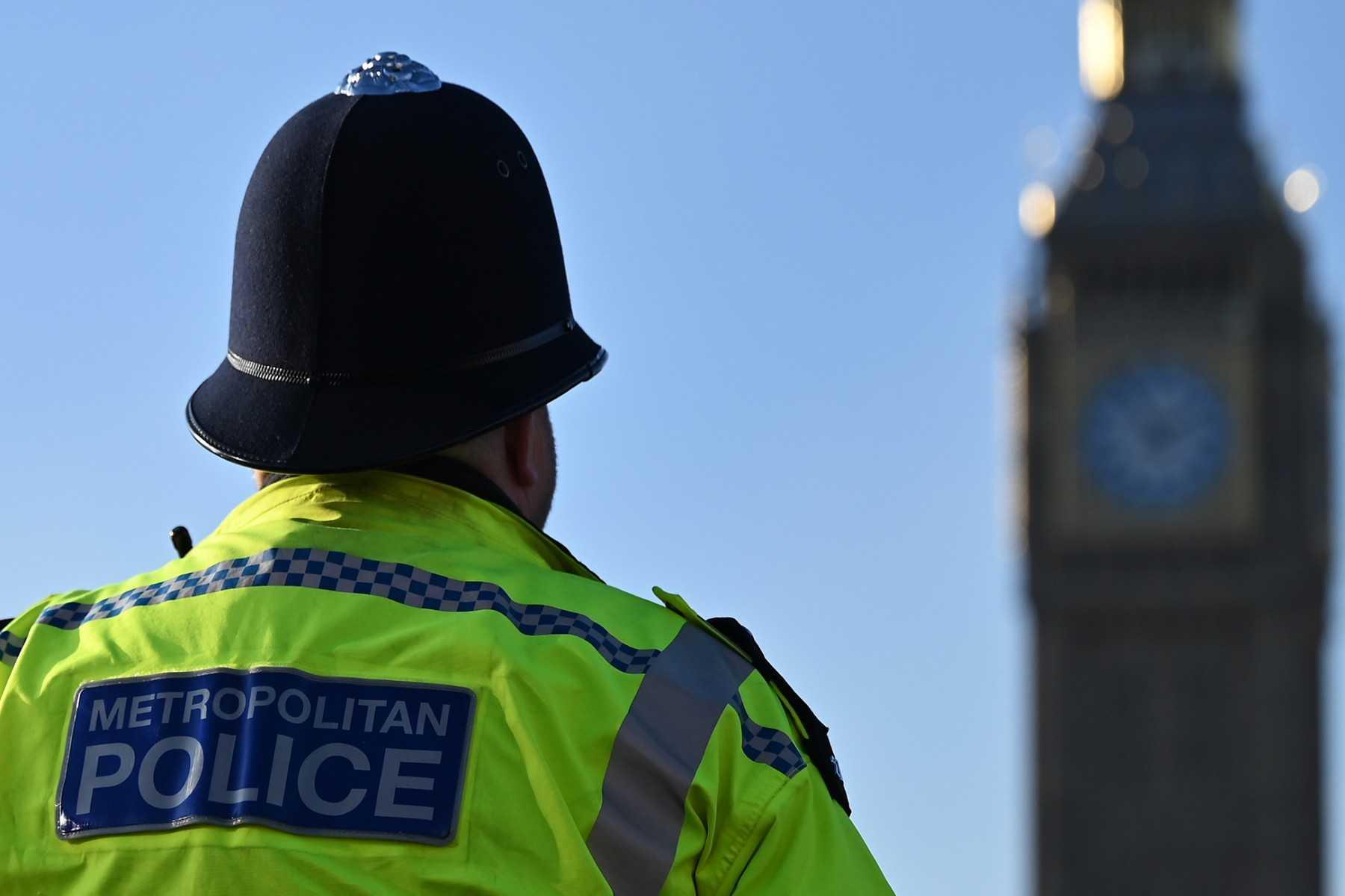 A Metropolitan Police officer walks beside a protest march near Big Ben and the Houses of Parliament, in central London, on Jan 21. Photo: AFP
