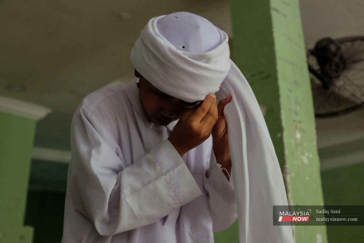Another student winds a turban about his head as he, too, prepares for the weekly prayers. 
