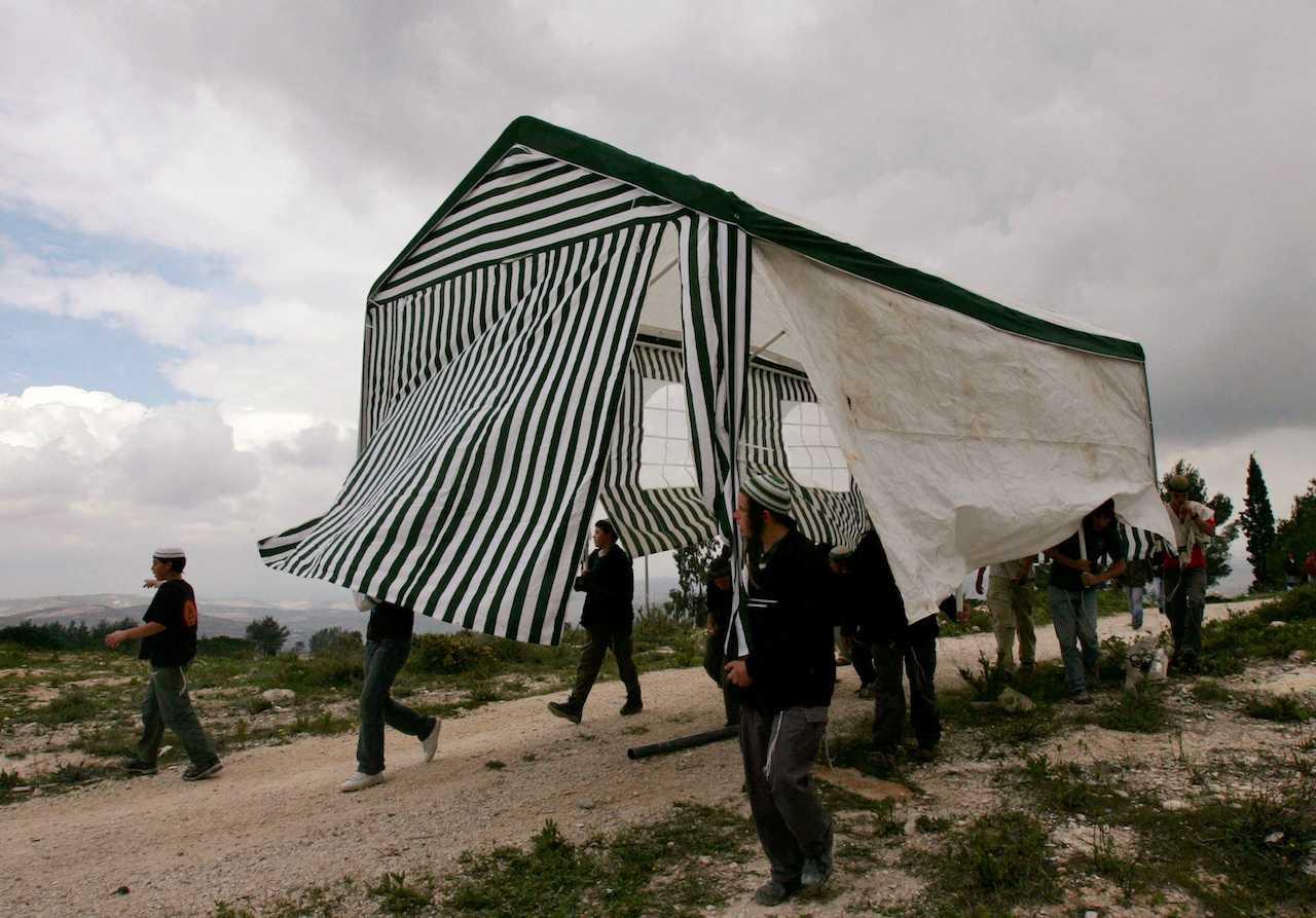Israeli activists carry a tent in the abandoned Jewish settlement of Homesh, in the northern West Bank, March 27, 2007. Photo: Reuters