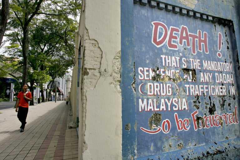 A pedestrian walks past a message on Malaysia's mandatory death penalty for drug trafficking on a wall of the historic Pudu jail in Kuala Lumpur on Nov 1, 2007. Photo: AFP
