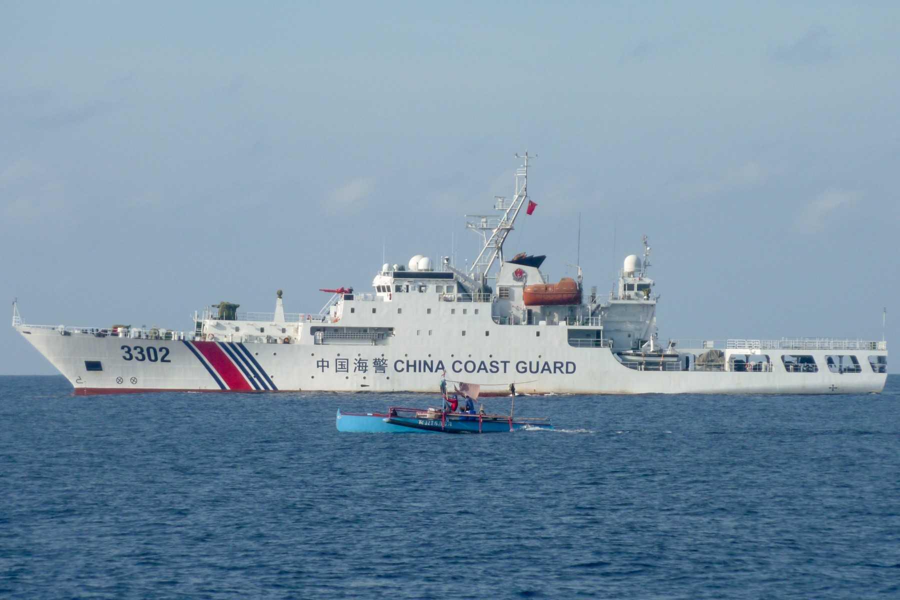 Gambar yang diambil pada 5 Februari, menunjukkan nelayan Filipina melepasi kapal pengawal pantai China di Scarborough Shoal, kawasan pertikaian di Laut China Selatan. Gambar: AFP