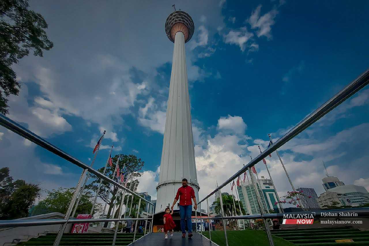 A visitor holds his daughter's hand at Menara Kuala Lumpur where an official observation session to determine the new moon for Ramadan is held each year. 