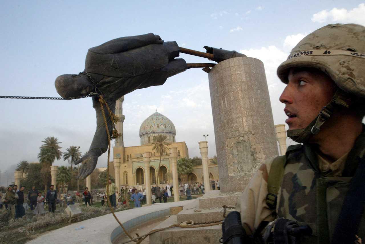 Seorang askar AS melihat patung Presiden Iraq Saddam Hussein jatuh di tengah Baghdad, 9 April 2003. Gambar: Reuters
