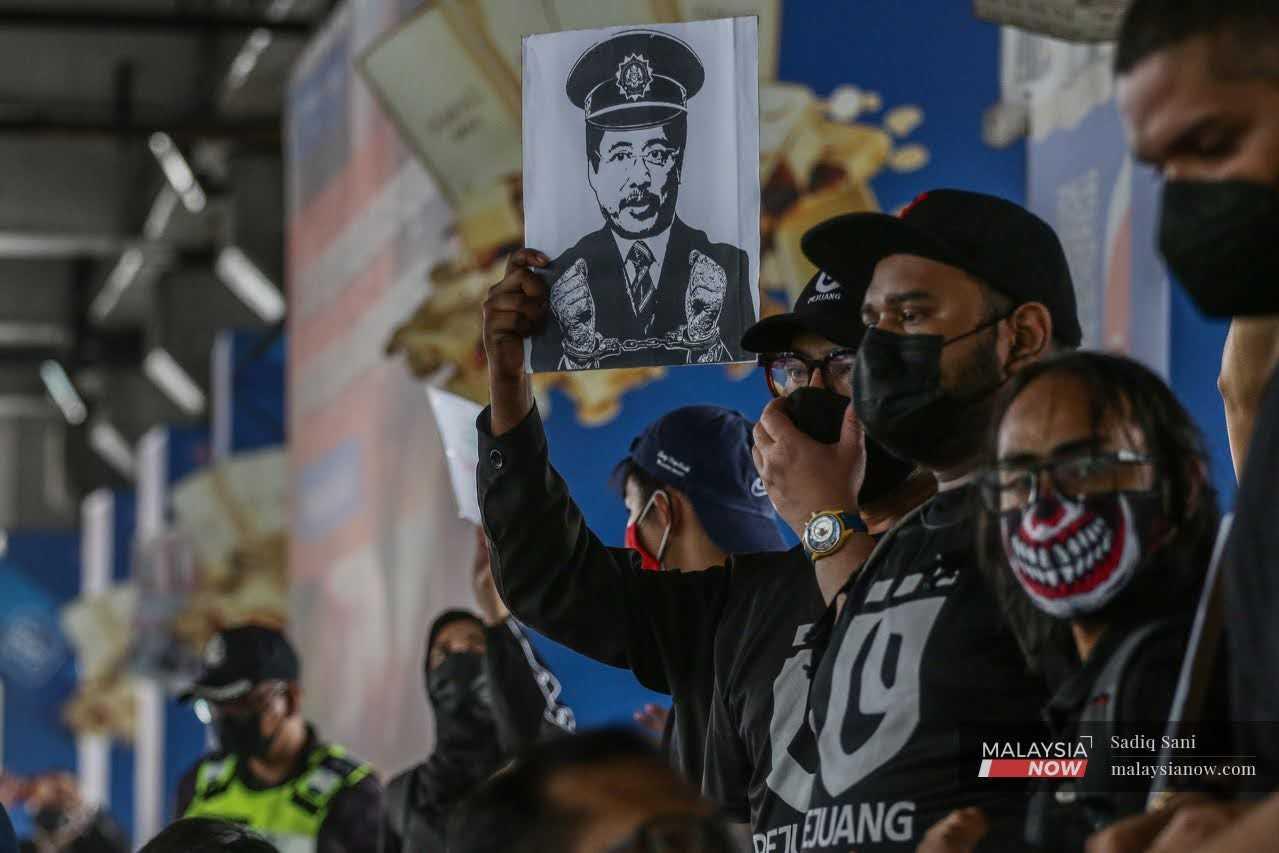 Seorang penunjuk perasaan memegang sepanduk yang tertera wajah Ketua Pesuruhjaya Suruhanjaya Pencegahan Rasuah Malaysia (SPRM), Azam Baki semasa perhimpunan #TangkapAzamBaki di Bangsar, 22 Januari 2022.