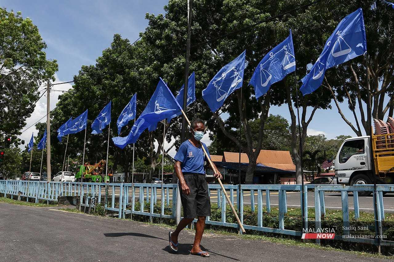 An election worker puts up Barisan Nasional flags ahead of the Melaka state election in November 2021.