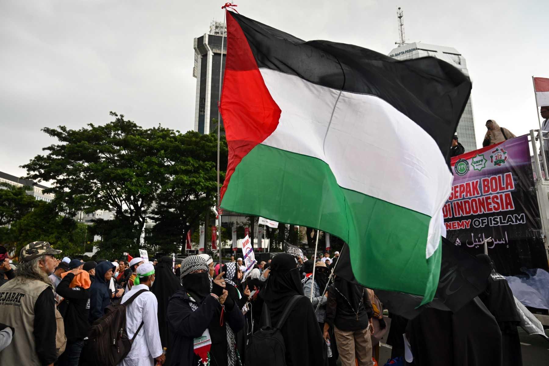 An Indonesian woman holds the flag of Palestine during a rally in Jakarta on March 20, to demand the Indonesian government to reject the participation of Israel's team in the upcoming 2023 Fifa U-20 World Cup, which is to be hosted by Indonesia between May 20 and June 11. Photo: AFP 