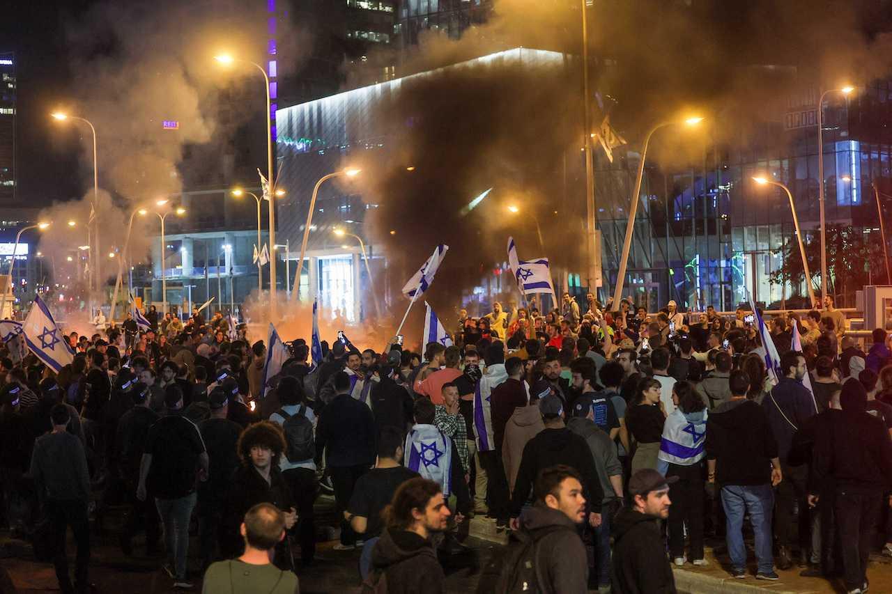 Protesters surround a burning fire during a demonstration against Israeli Prime Minister Benjamin Netanyahu and his nationalist coalition government's plan for judicial overhaul, in Tel Aviv, March 27. Photo: Reuters