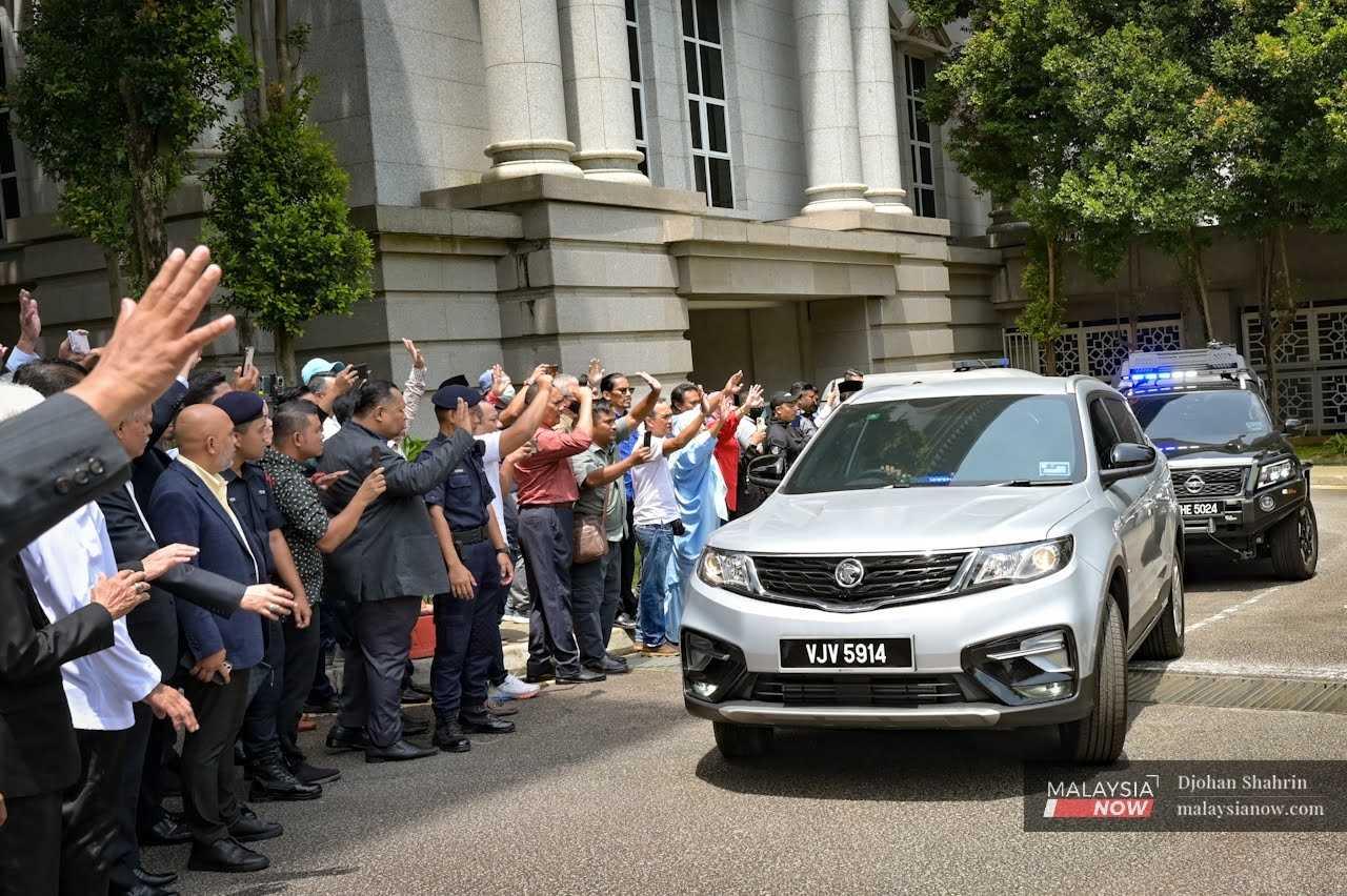 Najib Razak's supporters wave as the former prime minister's vehicle leaves the court complex in Putrajaya, March 31.