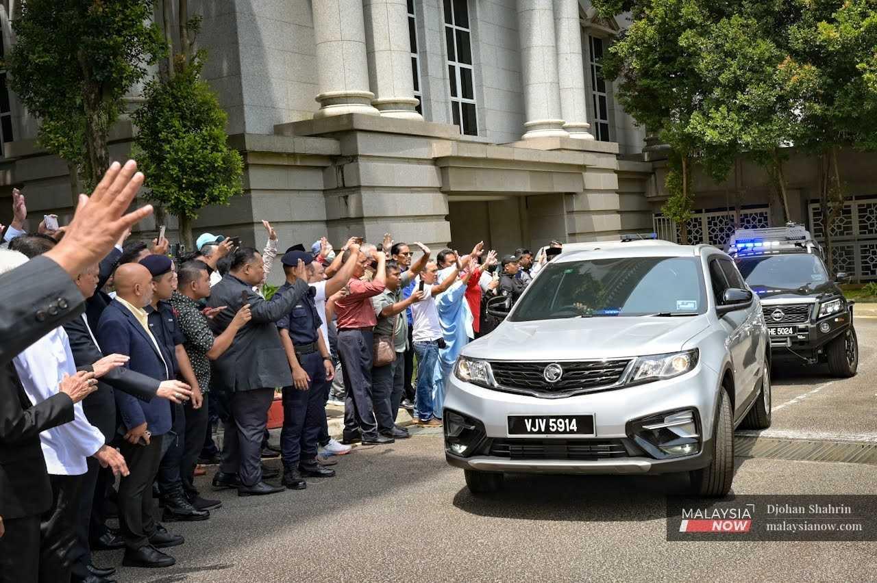 Penyokong Najib Razak melambai ketika kenderaan bekas perdana menteri meninggalkan Istana Kehakiman di Putrajaya, 31 Mac.