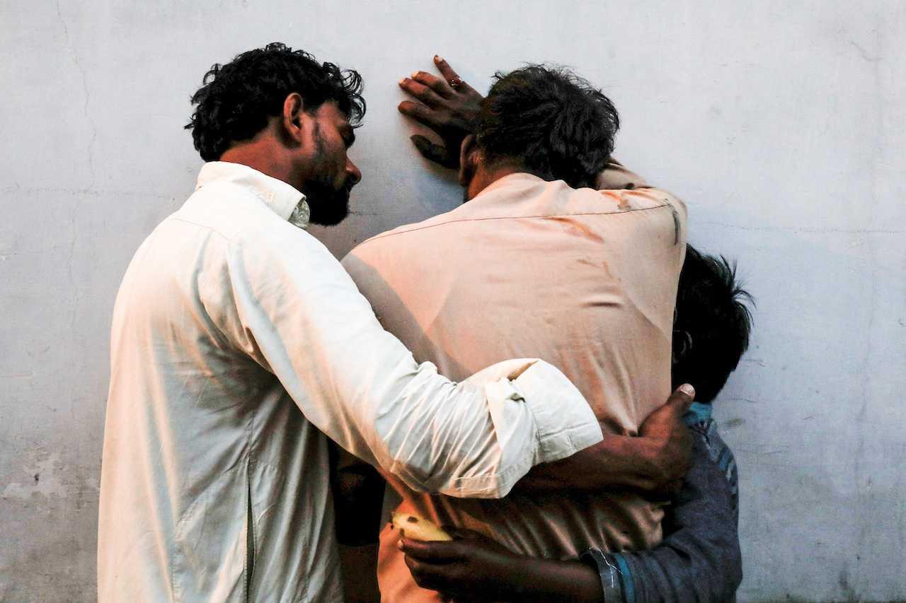 People comfort each other as they mourn the death of relative who was killed along with others in a stampede during handout distribution, at a hospital morgue in Karachi, Pakistan, March 31. Photo: Reuters