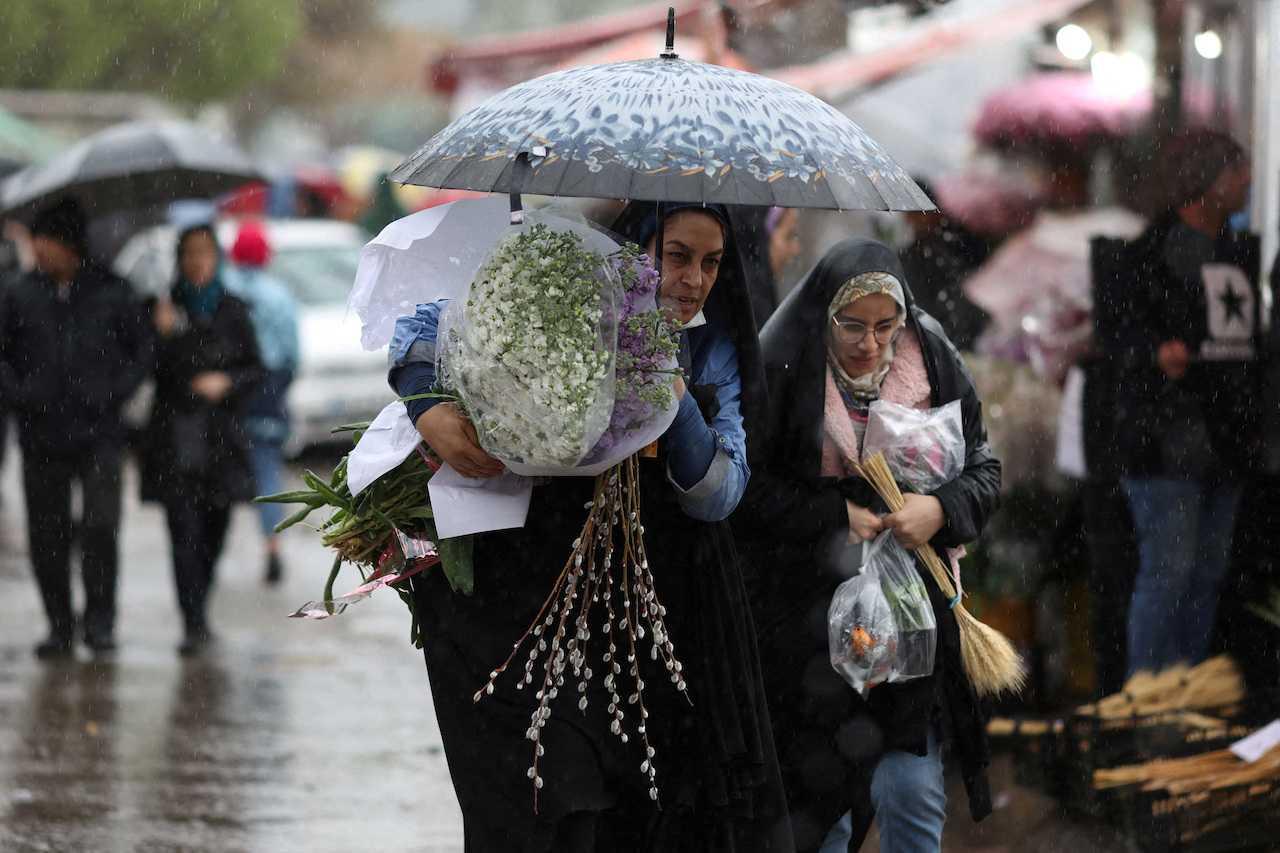 Iranian women walk through rain in a flower market, ahead of Nowruz, the Iranian New Year, in Tehran, March 16. Photo: Reuters