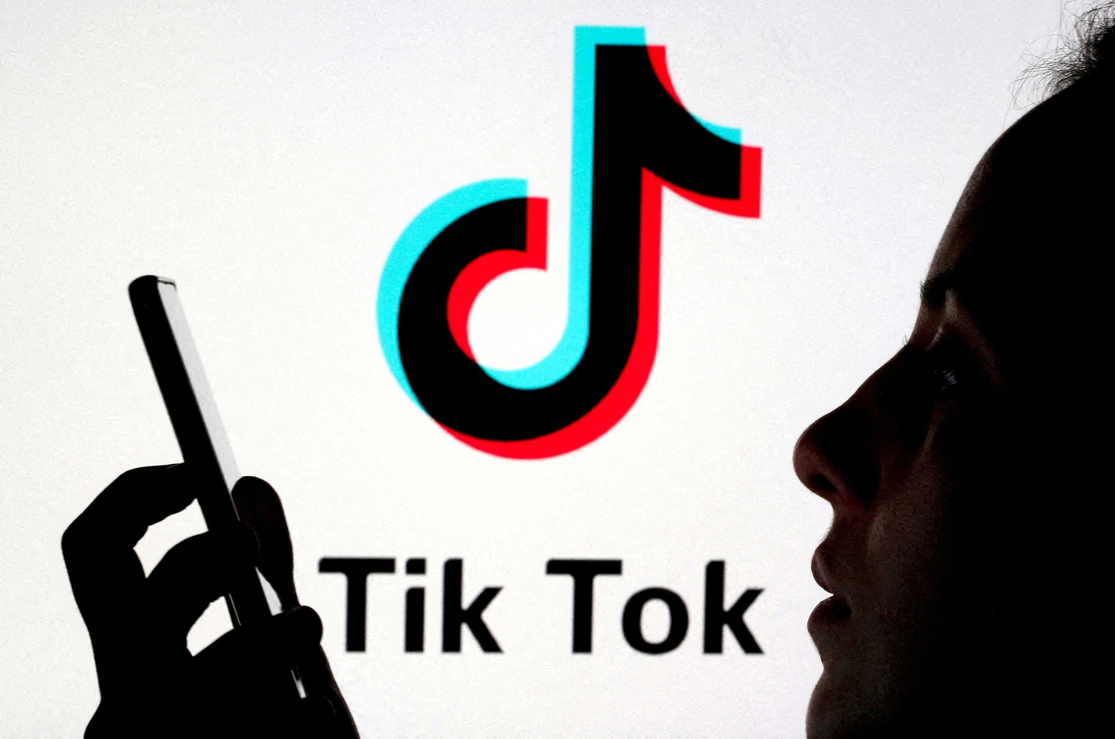 A person holds a smartphone as a TikTok logo is displayed behind in this picture illustration taken Nov 7, 2019. Photo: Reuters
