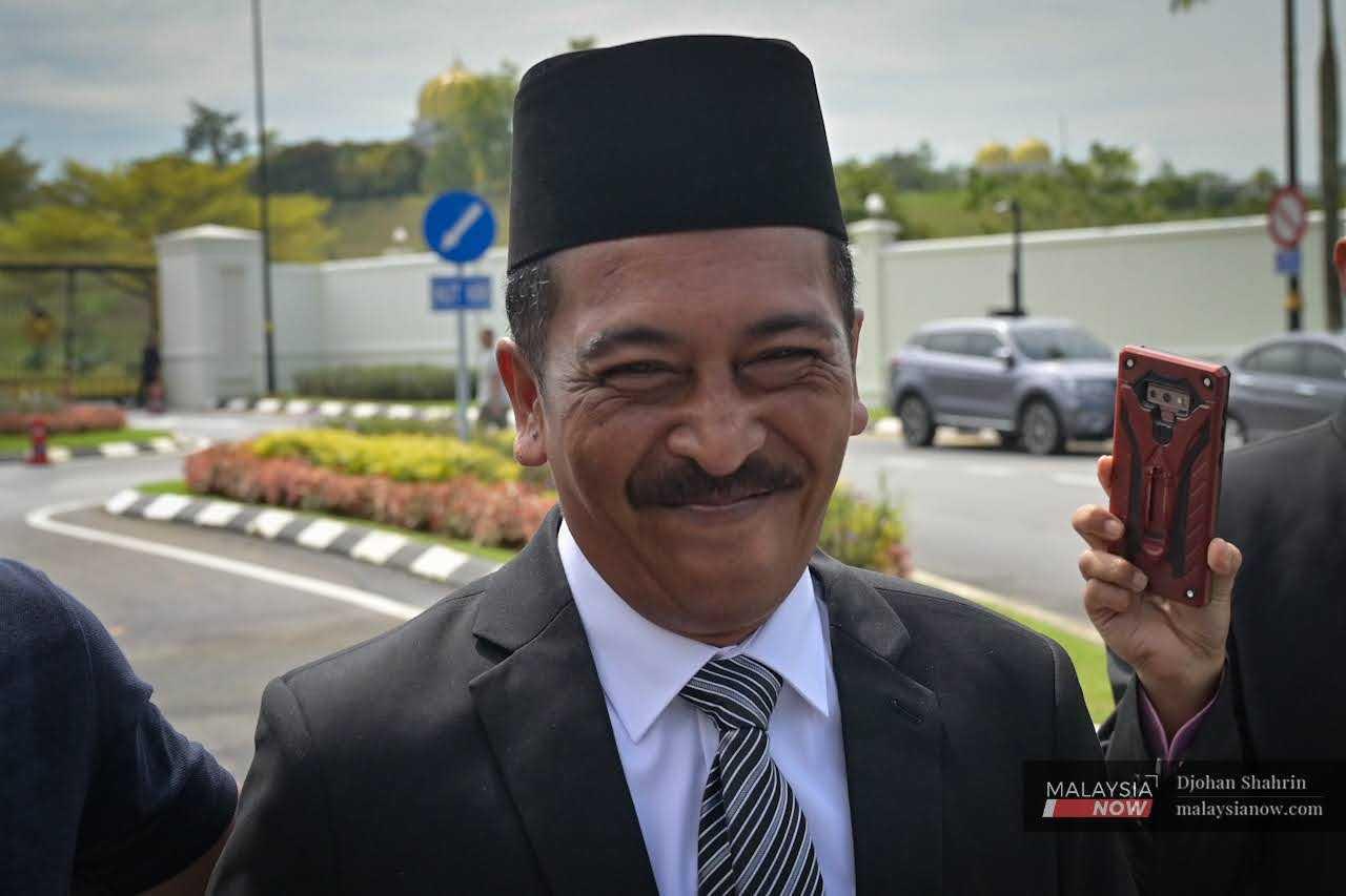 Taxi driver Noorazlan Ismail smiles upon his arrival at Istana Negara in Kuala Lumpur.