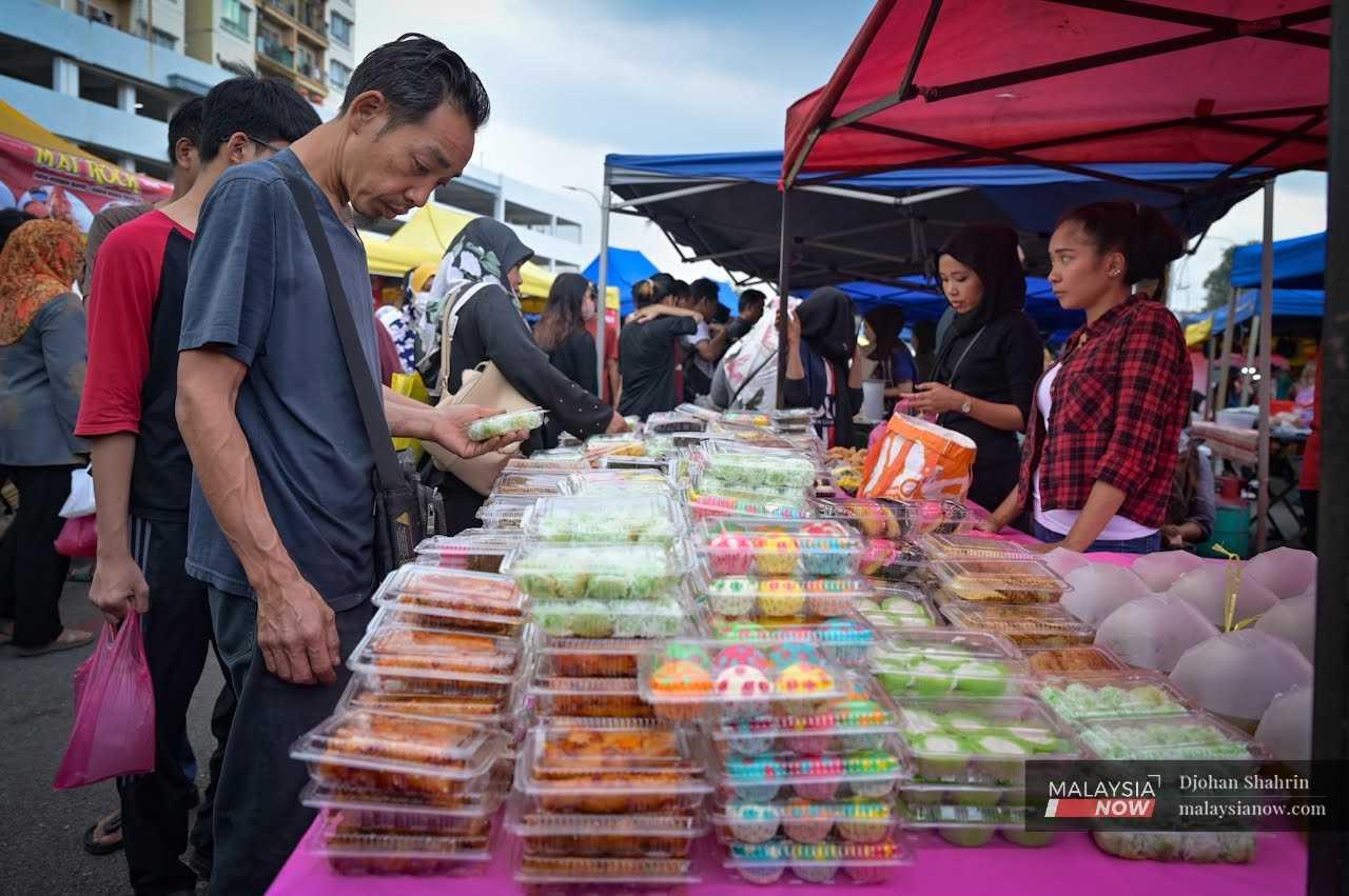 At another stall, a customer chooses from a variety of traditional kuih.